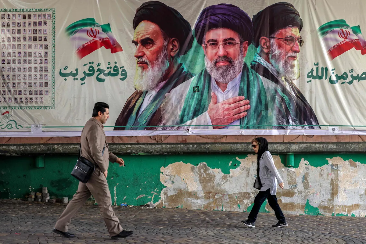 netanyahunun-iran-talimati-ve-abdnin-saldiri-plani-iddiasi-1792683310201.jpg İran’ın eski dini lideri Ayetullah Ruhullah Humeyni (solda), mevcut lider Mücteba Hamaney (ortada) ve hayatını kaybeden Ali Hamaney’in (sağda) portrelerinin yer aldığı pankartın önünden geçen yayalar, Tahran, 21 Ekim 2026. (Foto: AFP)