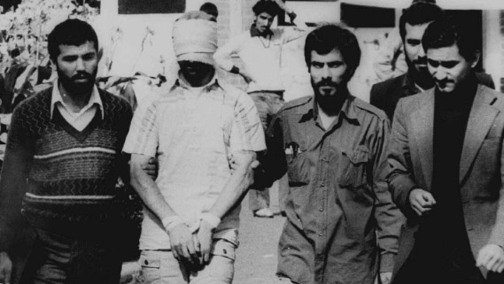 jimmy-carterin-tarihe-biraktigi-izler-el-kaidenin-kurulmasindan-bosna-hersek-savasina-1735543115553.jpg 9 Kasım 1979 tarihli bu fotoğrafta, İslamcı radikallerin Tahran'daki ABD Büyükelçiliği'ne baskın düzenlemesi sırasında rehin alınanlardan biri, gözleri bağlı ve elleri bağlı bir şekilde, İranlı rehineciler tarafından Tahran'daki ABD Büyükelçiliği'nin dışında kalabalığa gösteriliyor. Başkan Carter, İran'daki Amerikan rehinelerinin serbest bırakılmasını sağlamaya çalışıyordu. Ronald Reagan göreve başlayana kadar serbest bırakılmadılar. (AP)