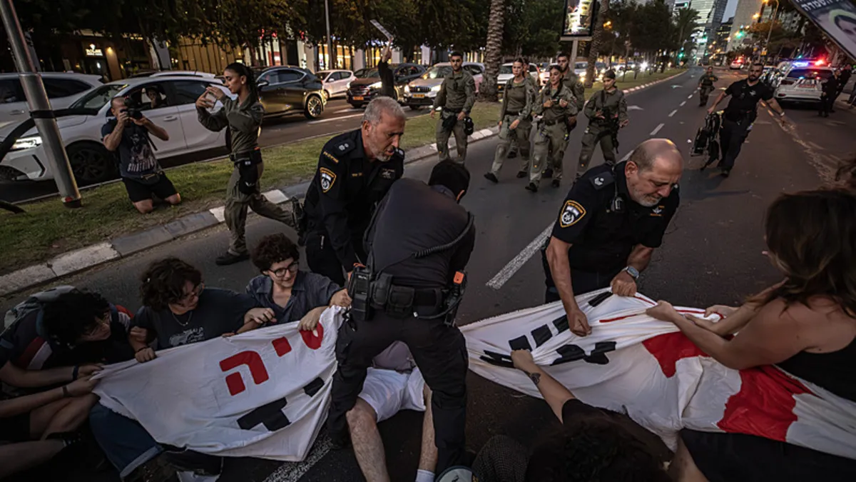 Tel Aviv'de bir yolu kapatan göstericilere polisin müdahalesi ve pankartın çekiştirilmesi